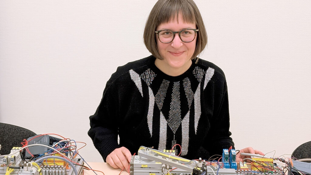 Sara Svensson sitter framför teknisk utrustning där hon kan träna på automatiserade flöden.