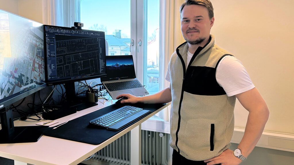 Erik Lindström som läser till Elkonstruktör på TUC Yrkeshögskola i Skellefteå står vid ett skrivbord med tre datorskärmar. På skärmarna syns CAD-ritningar